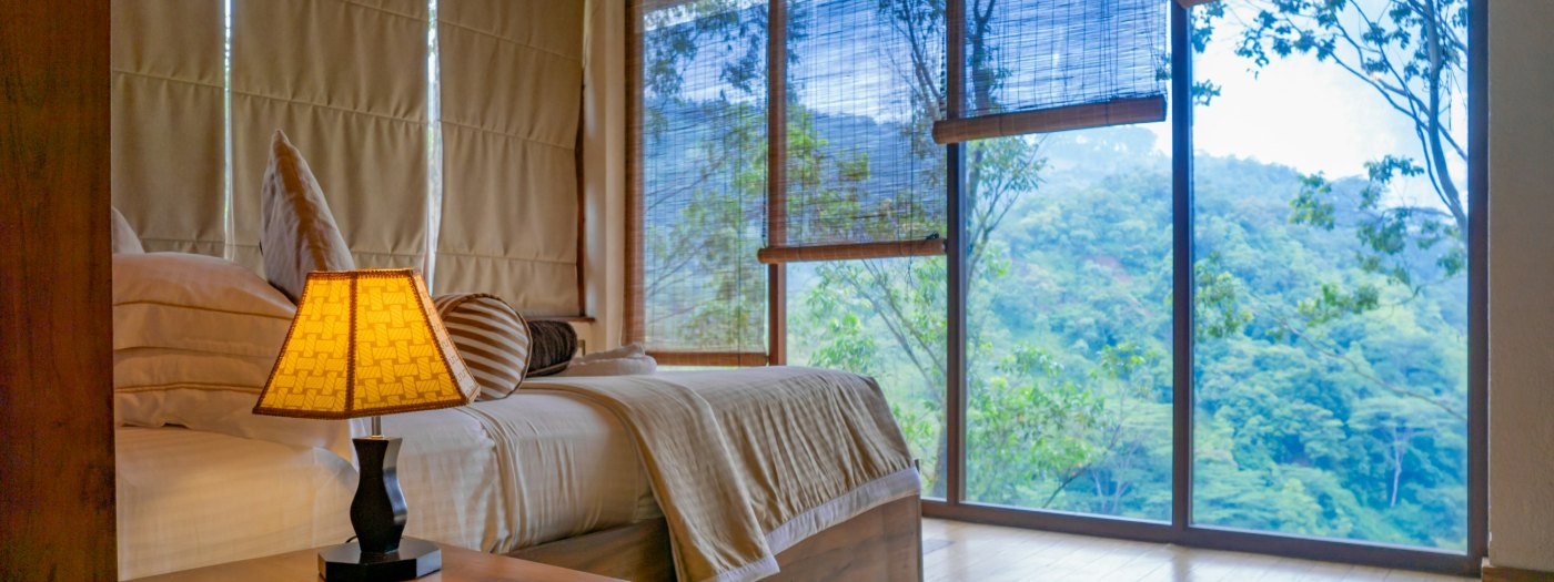A lamp-lit room looking out onto forested hills