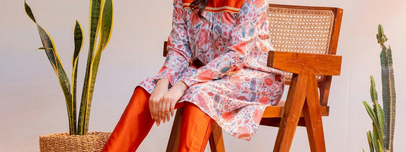 Woman models stylish clothing and sits on a chair
