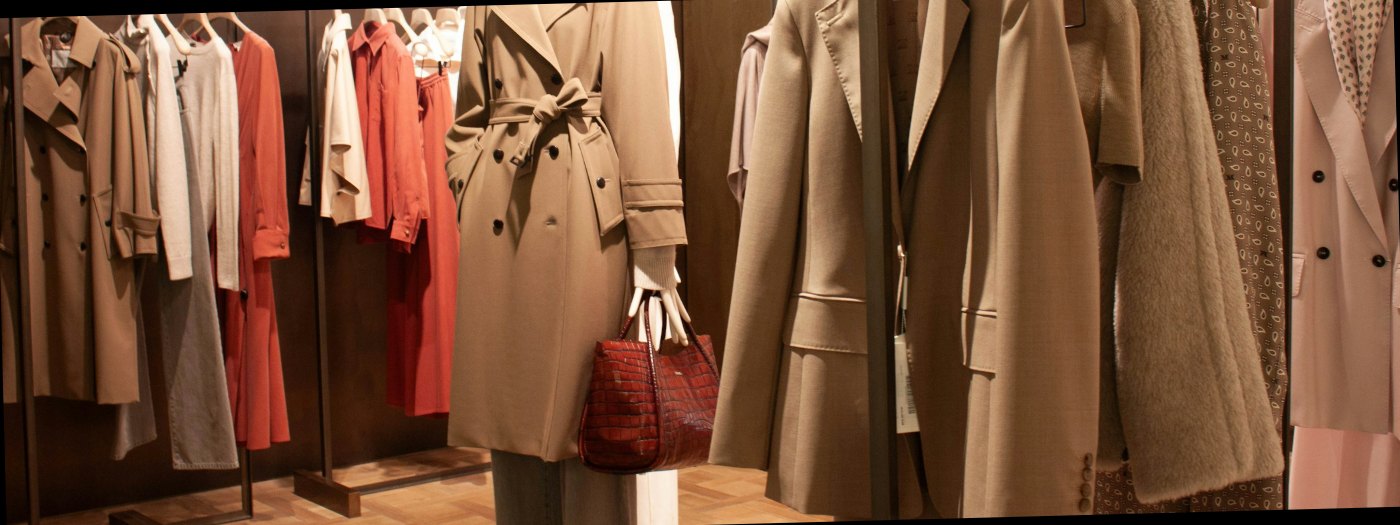 Rails of women's coats and separates in a wood-lined store