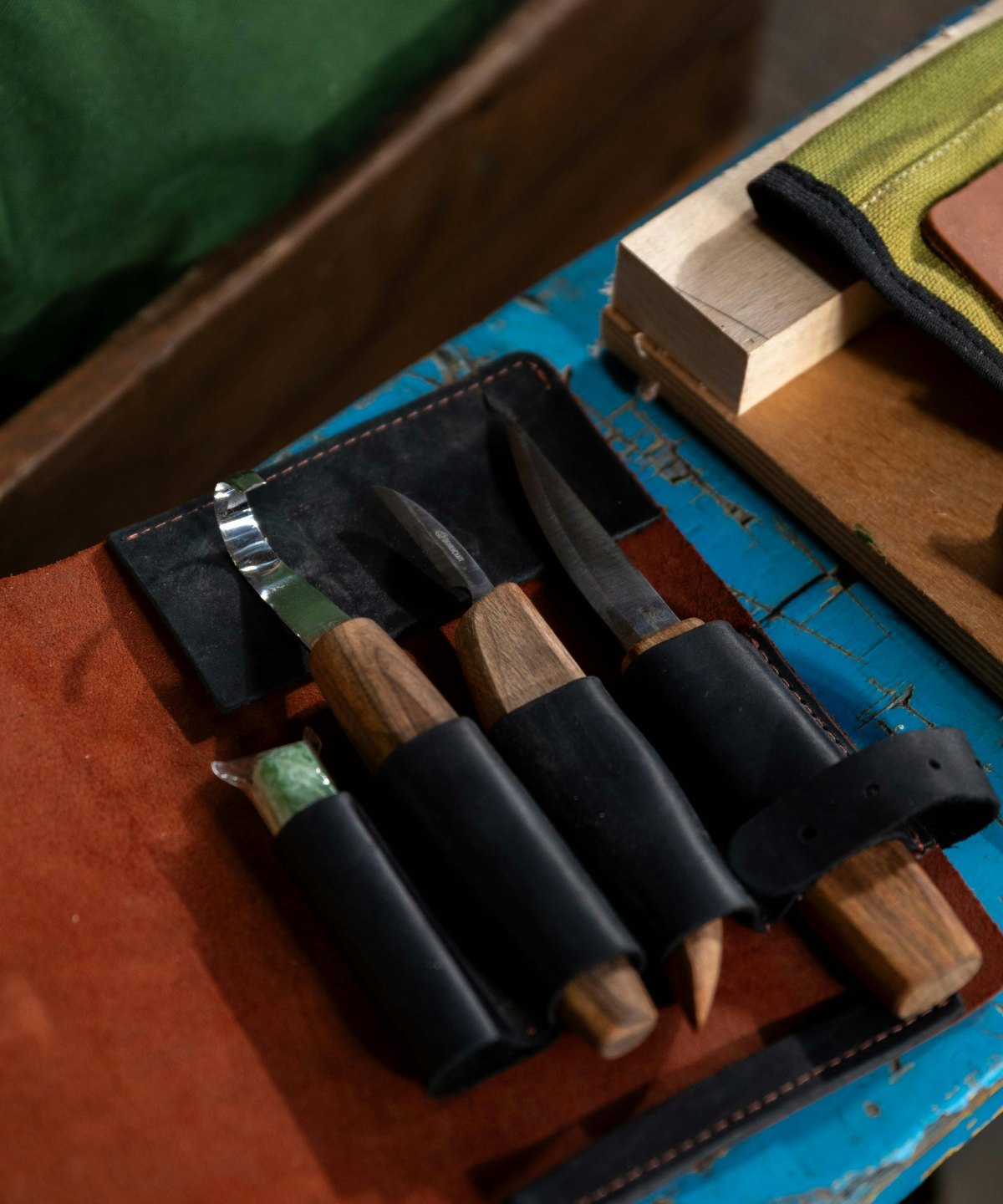 A roll of craft tools laid open on a worn surface