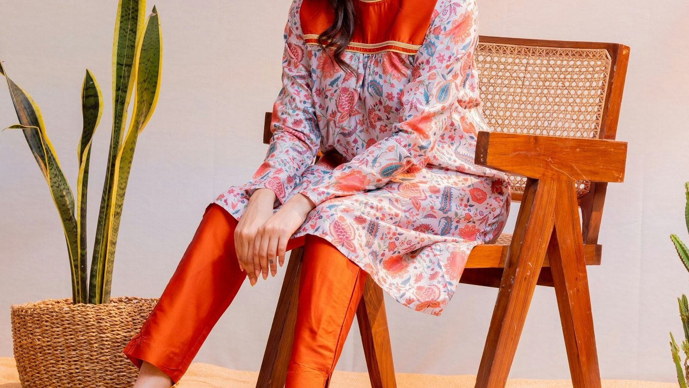 Woman models stylish clothing and sits on a chair